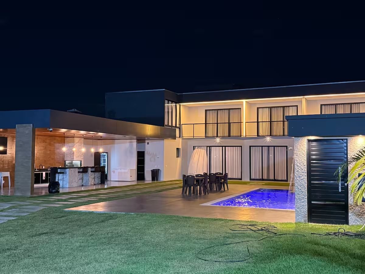 A modern house with a pool, outdoor seating, and a well-lit entrance.