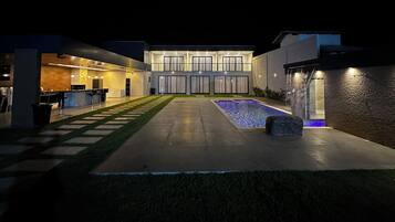 Un'area piscina moderna all'aperto con un vialetto in pietra che conduce a un angolo bar.
