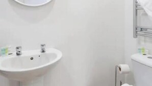 A bathroom with a round mirror, a sink, and a toilet. - The residency rooms liverpool  (Liverpool)
