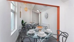 A modern dining area with a round glass table, black chairs, and a white wall clock. - The residency rooms liverpool  (Liverpool)