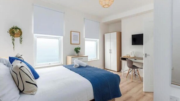 A modern bedroom with a bed, bedside table, and a desk area with a chair. - The residency rooms liverpool  (Liverpool)