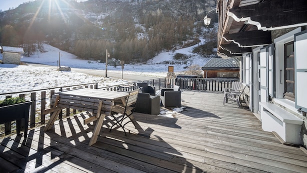 Une terrasse en bois avec des sièges extérieurs, offrant une vue sur un paysage enneigé et une montagne.