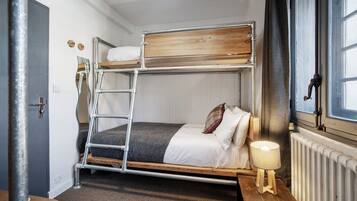 Un lit superposé avec une échelle, une table de chevet avec une lampe et une fenêtre avec des rideaux.