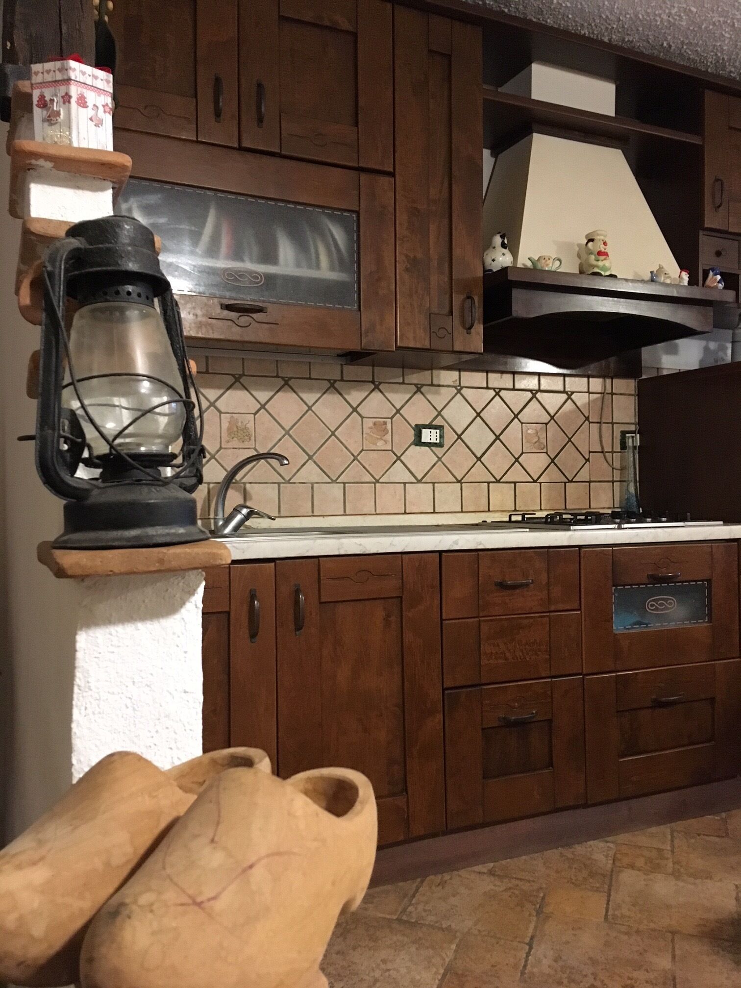 Une cuisine avec des meubles en bois, un pare-feu en carreaux, une cuisinière et une lanterne.