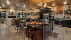 A spacious kitchen with a large island, modern appliances, and a cozy dining area. - 26 Guests | Resort Waterpark | Indoor Pool | Views (Sevierville)