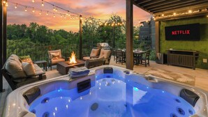 A hot tub with a fire feature, outdoor seating, and a Netflix sign on the wall. - 26 Guests | Resort Waterpark | Indoor Pool | Views (Sevierville)