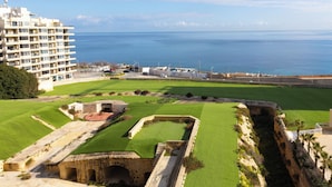 A coastal hotel with a view of the sea, a well-maintained lawn, and a historical fortification. - Fort Cambridge (Sliema)