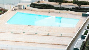 A large rectangular swimming pool with a tiled deck area, surrounded by a low wall and a few lounge chairs. - Fort Cambridge (Sliema)