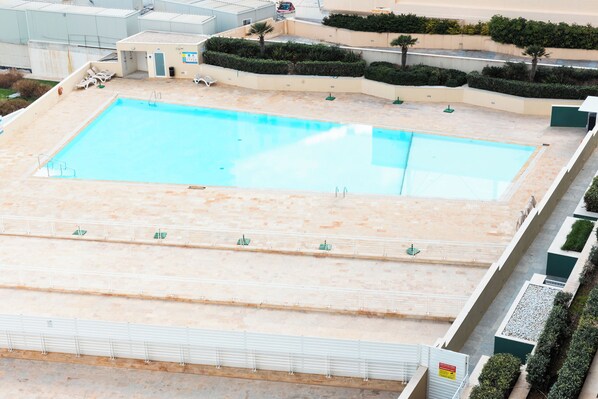 A large rectangular swimming pool with a tiled deck area, surrounded by a low wall and a few lounge chairs. - Fort Cambridge (Sliema)