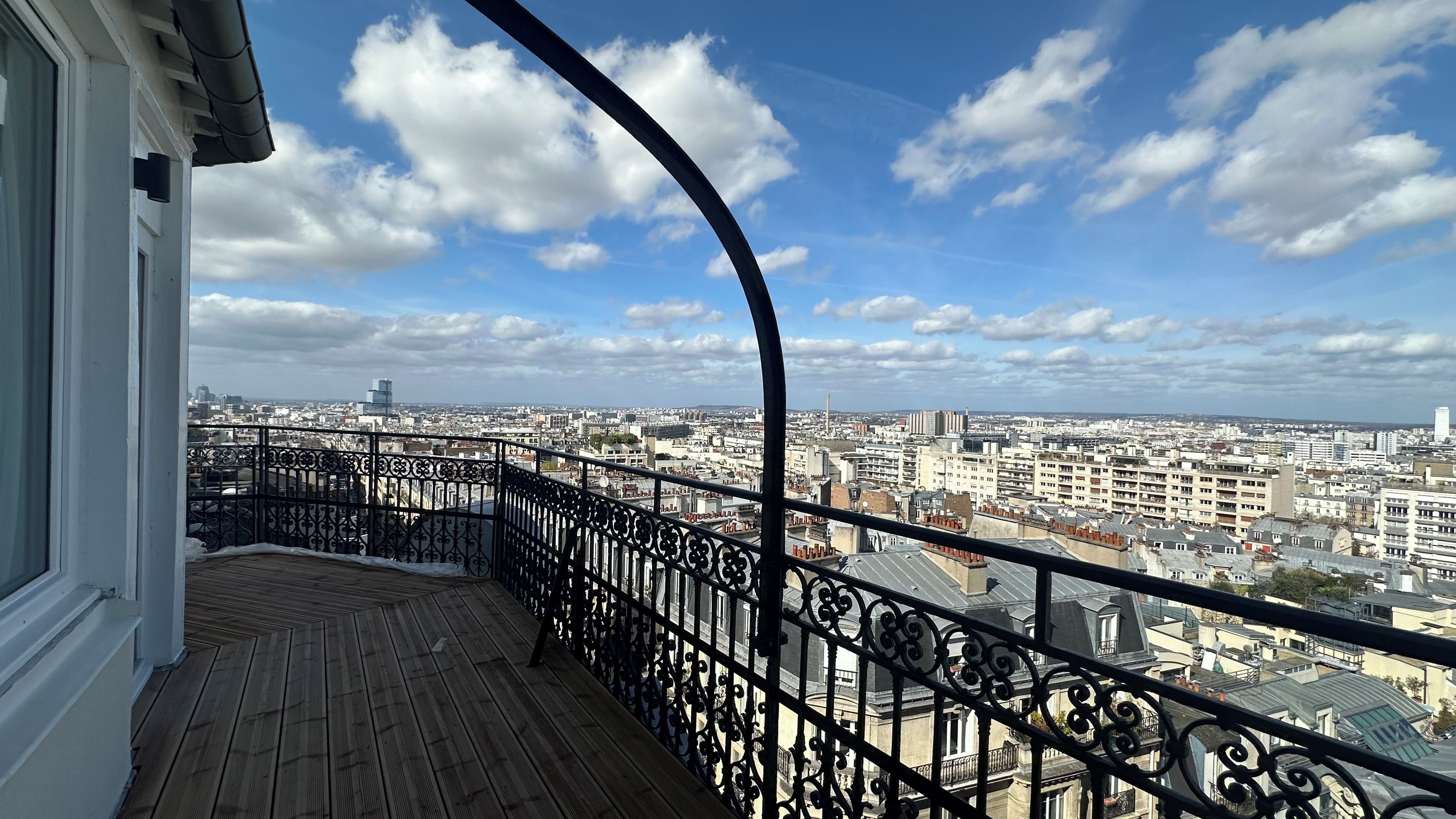 A balcony with a wrought iron railing overlooking a cityscape.