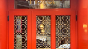 A red hotel entrance with a glass door and a sign above it. - BOHEM Sacré Coeur (Paris)