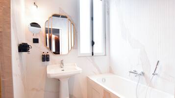 Une salle de bain avec une baignoire, un lavabo, un miroir et une fenêtre.
