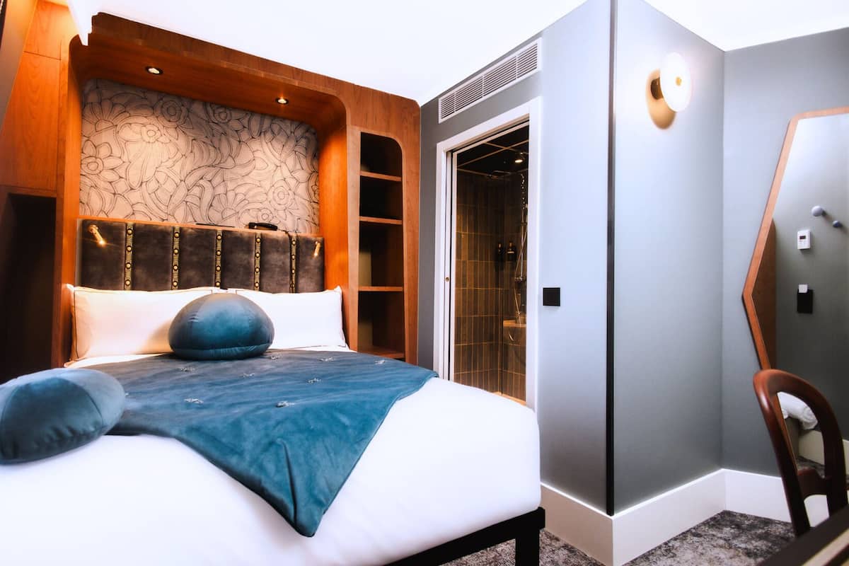 A bedroom with a bed, a wooden headboard, a wardrobe, and a chair.