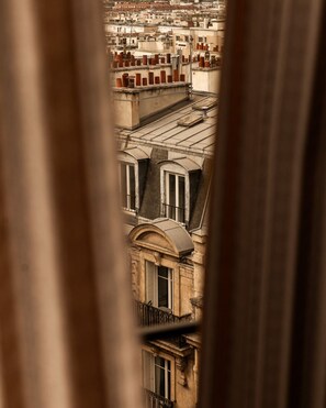 A view through a window of a building with multiple floors, featuring balconies and a mix of architectural styles. - BOHEM Sacré Coeur (Paris)