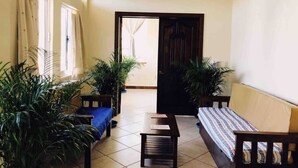 A spacious room with a tiled floor, a wooden table, a sofa, and two potted plants. - King beds, Starlink, Ocean Views, Steps to beach. (Puerto escondido Oaxaca)