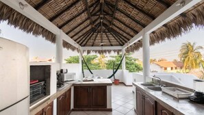 A kitchen with a thatched roof, wooden cabinets, and a tiled floor. - King beds, Starlink, Ocean Views, Steps to beach. (Puerto escondido Oaxaca)