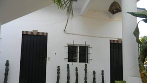 A building with a black door and window, surrounded by cacti and a plant. - Steps from the beach - easy checkin (Brisas de Zicatela)