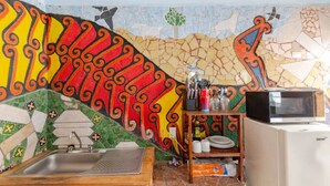 A bathroom with a mosaic wall, a sink, a wooden stool, and a shelf with toiletries. - Steps from the beach - easy checkin (Brisas de Zicatela)