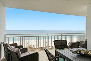 Ein Balkon mit Korbmöbeln und Blick auf einen Strand.