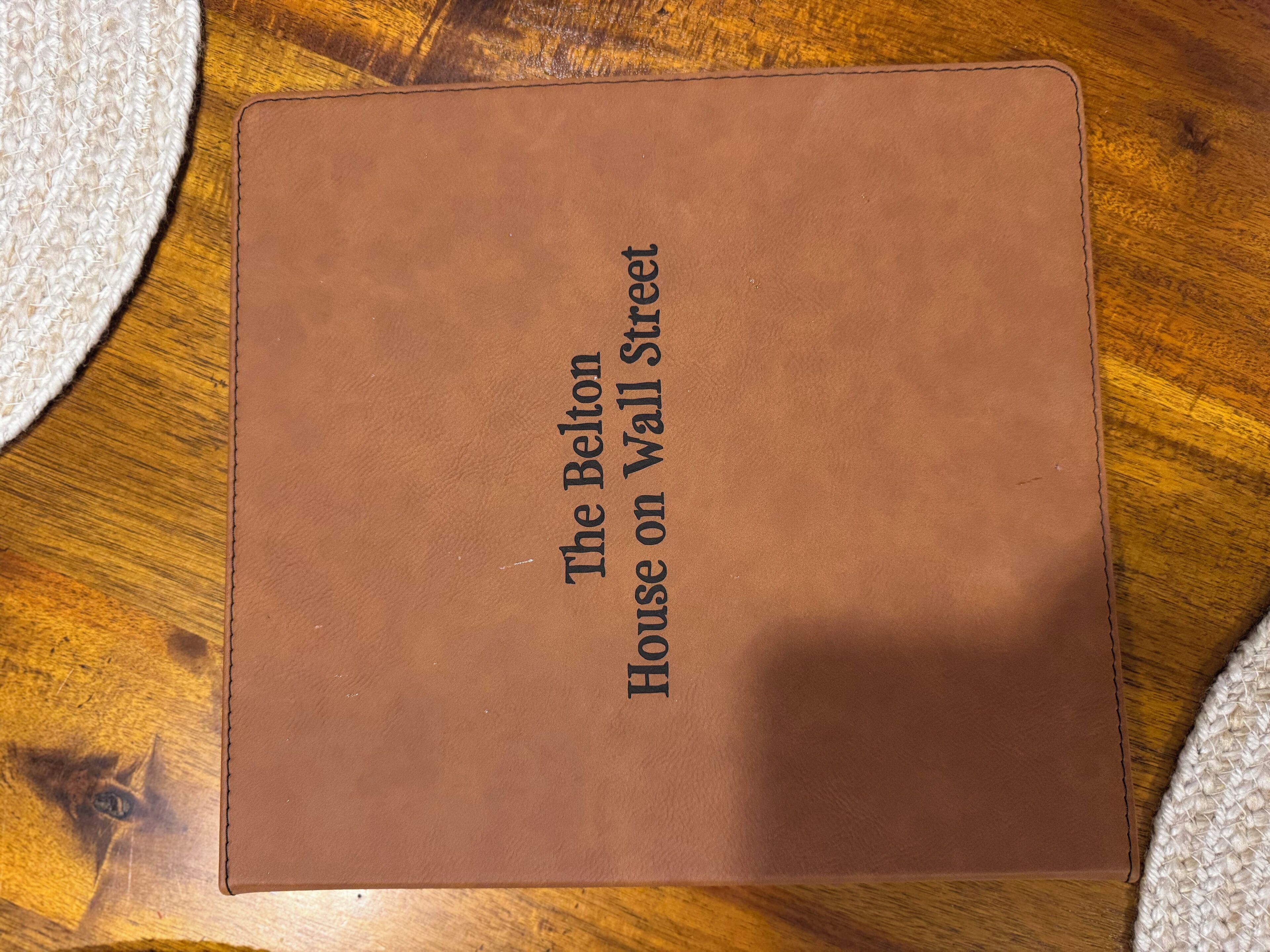 A brown leather folder with the text "The Belton House on Wall Street" on it.