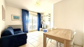 Una sala de estar con un sofá, una mesa de comedor de madera y un televisor.