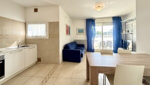 Una cocina moderna con armarios blancos, horno integrado y una ventana con cortinas azules.