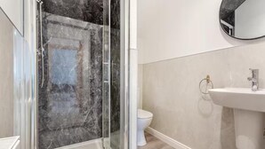 Ein modernes Badezimmer mit einer Duschkabine aus Glas, einem weißen Waschbecken und einer Toilette.