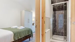 Ein Schlafzimmer mit Bett, Kleiderschrank und einer Duschkabine mit Glastür.