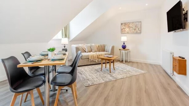 Ein modernes Loft-Apartment mit Essbereich, einer Couch und einem an der Wand befestigten Fernseher.