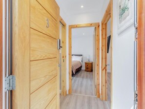 A hallway with wooden doors, a bed, a bedside table, and a wall-mounted TV. - Family - Central - Parking - Wifi - Sleeps 3 (Inverness)