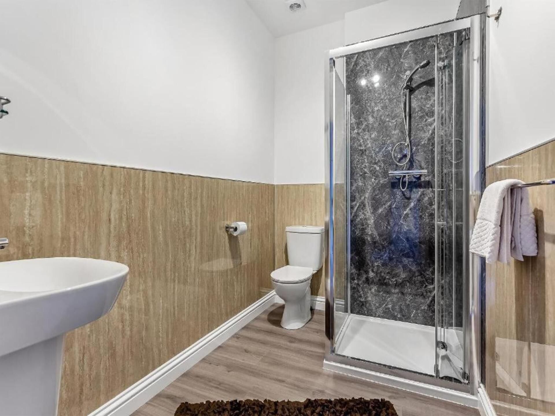 Une salle de bain moderne avec une douche à parois de verre, un lavabo blanc et des toilettes.