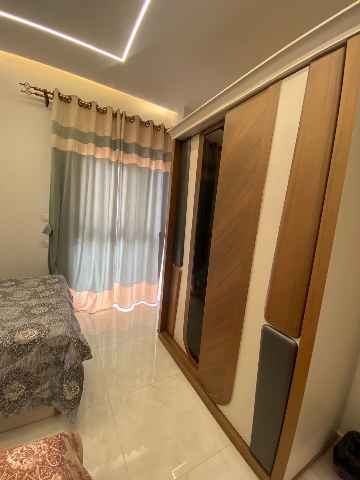 Un dormitorio con cama, armario y cortina.