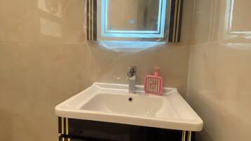 A bathroom with a white sink, black cabinet with gold handles, and a mirror with a blue light.