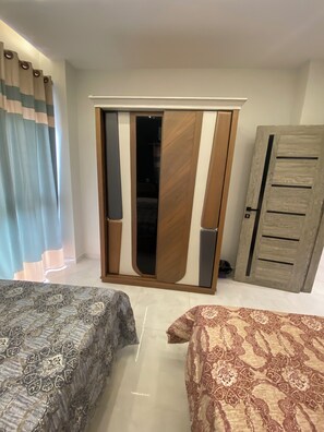 A hotel room with two beds, a wardrobe, and a door. - Spacious 3-bedroom apartment in soothing Hurghada with AC (Hurghada)