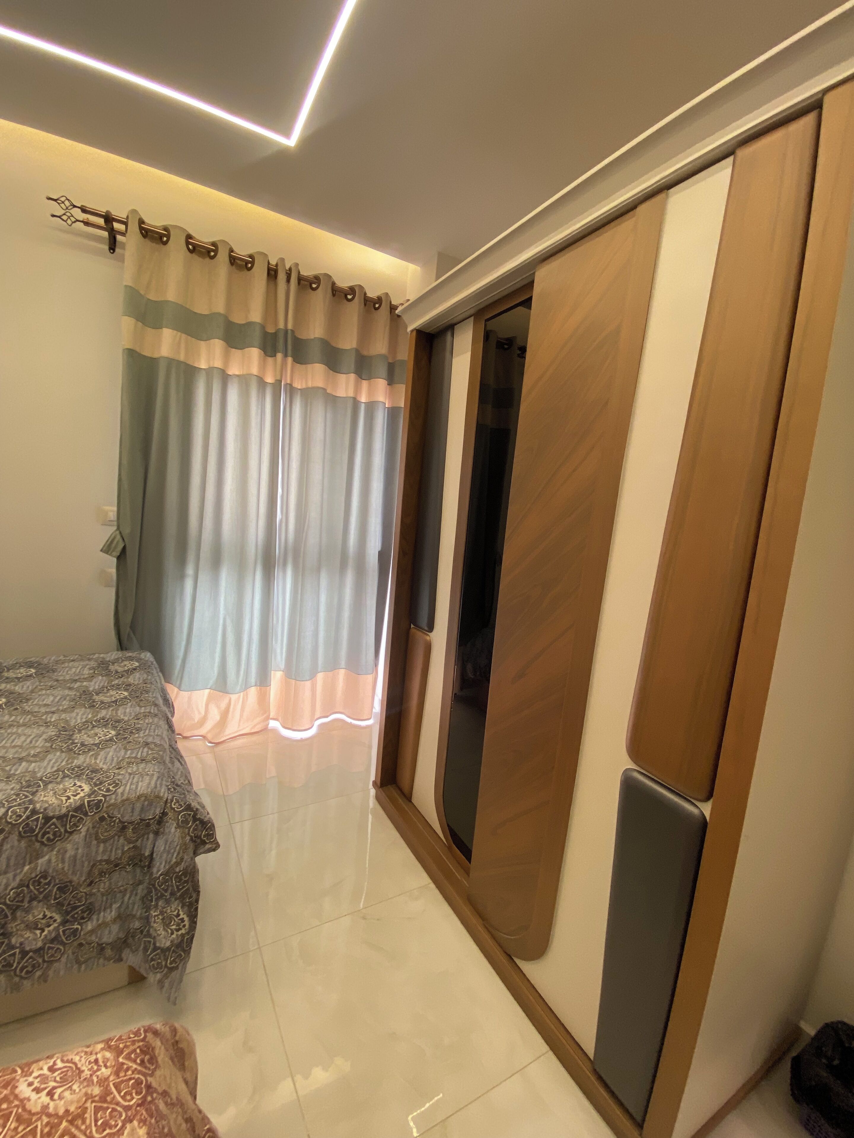 A bedroom with a bed, a wardrobe, and a curtain.