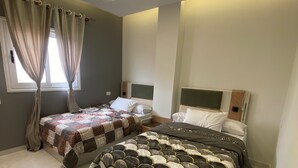 Een moderne hotelkamer met twee bedden, een groot raam met gordijnen en een licht plafond met lineaire verlichting.