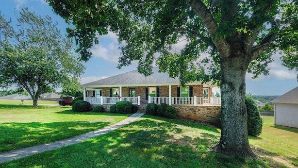 A two-story house with a front porch, a large tree, and a well-maintained lawn. - large Stunning Retreat 15 min to Downtown Huntsville 3br/3bath (Huntsville)