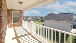 A covered porch with a brick wall, a window with blinds, and a view of a neighborhood. - large Stunning Retreat 15 min to Downtown Huntsville 3br/3bath (Huntsville)