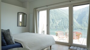 Una camera da letto con un letto, uno specchio e un balcone con sedie e un tavolo.