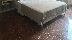Een slaapkamer met een bed, nachtkastjes, een lamp en een raam met gordijnen.