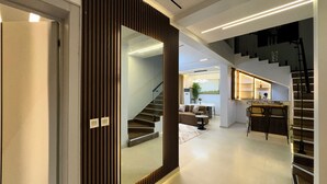 Um interior moderno com escada, sala de estar com sofá e mesa de centro, e cozinha com balcão.