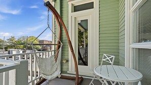 En balkon med hængekøje, et hvidt bord og en stol.