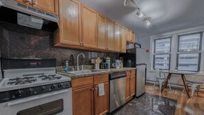A kitchen with wooden cabinets, a gas stove, a dishwasher, and a refrigerator. - Theater District Cozy 1 BR! (Boston)