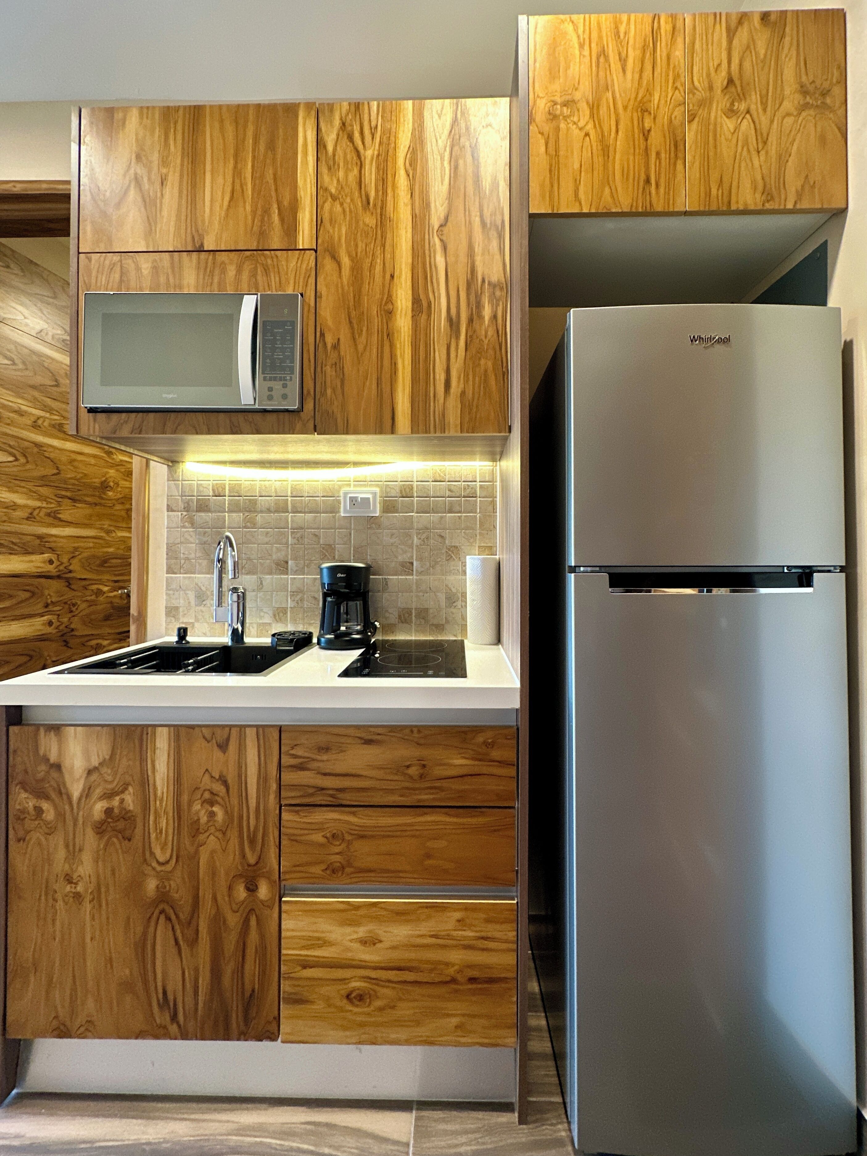 A kitchen with wooden cabinets, a microwave, a coffee maker, and a refrigerator.