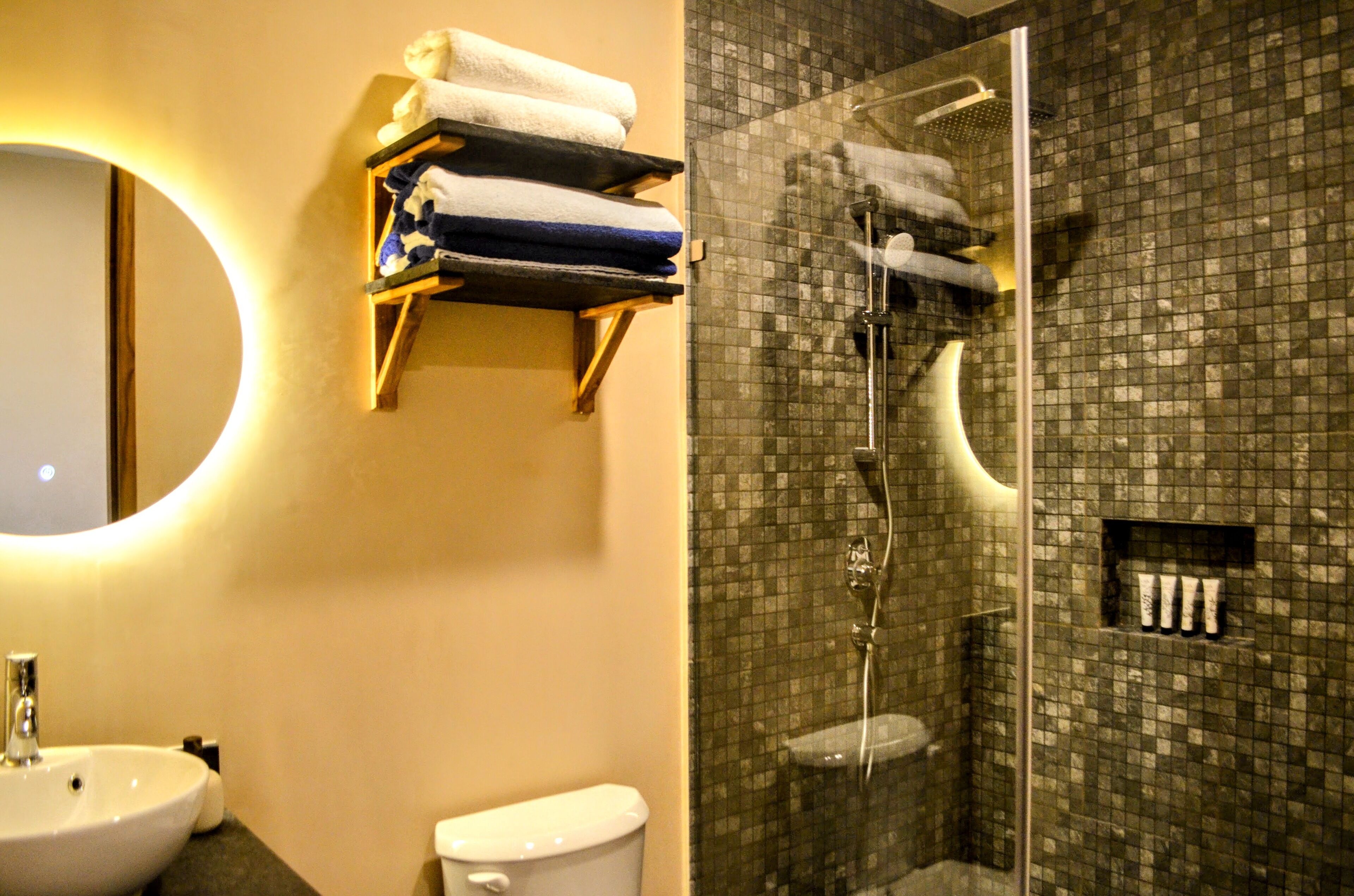 Un bagno con lavandino, WC e cabina doccia in vetro con rivestimento piastrellato.