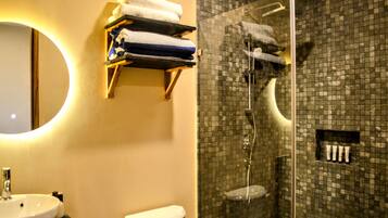 Un bagno con lavandino, WC e cabina doccia in vetro con rivestimento piastrellato.