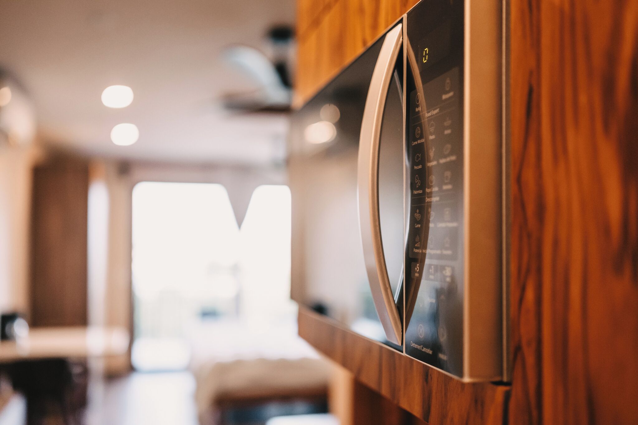 Una cocina moderna con refrigerador de acero inoxidable, armarios de madera y un panel de control a la vista.