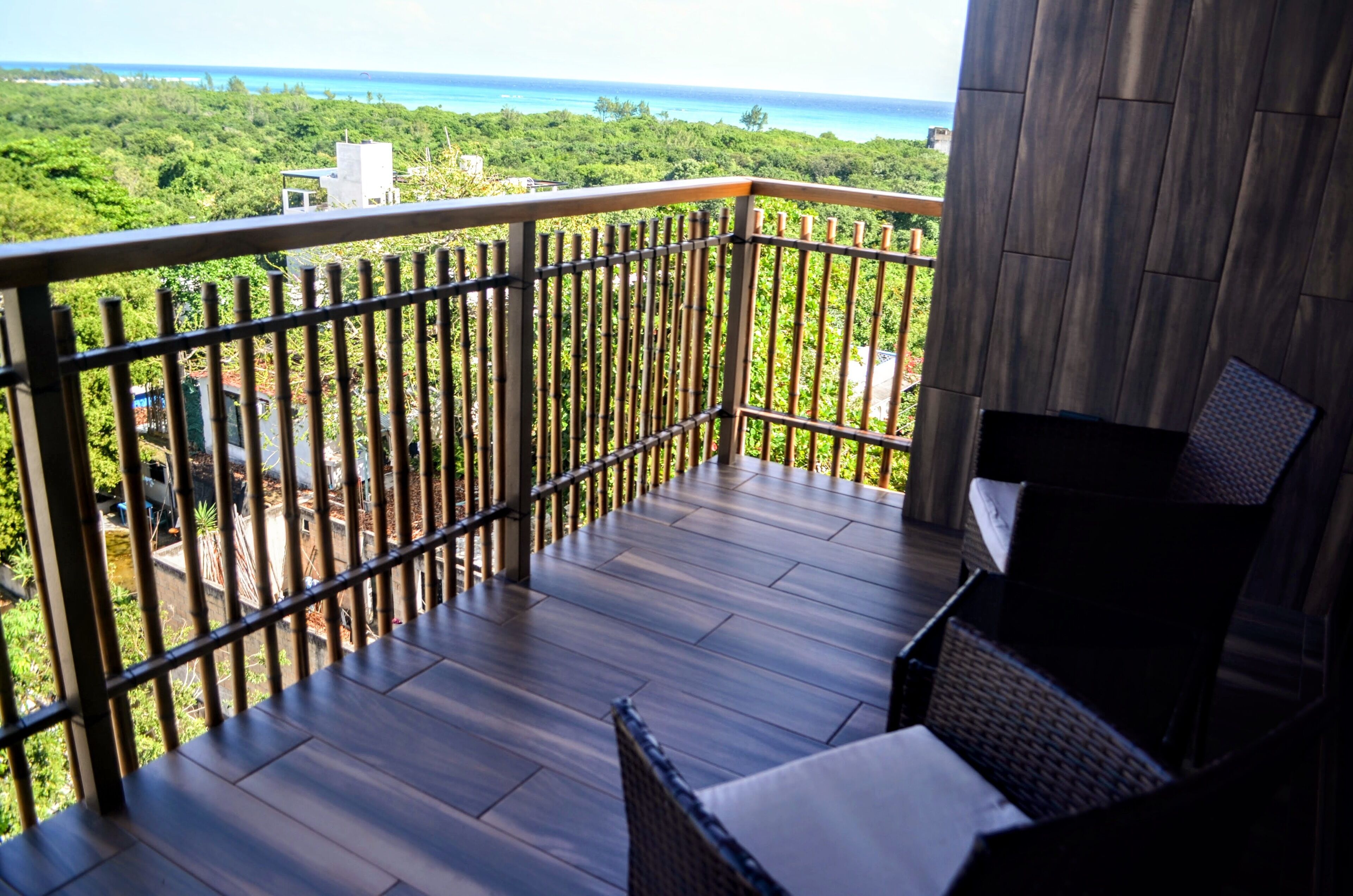 A balcony with a view of the ocean and greenery.