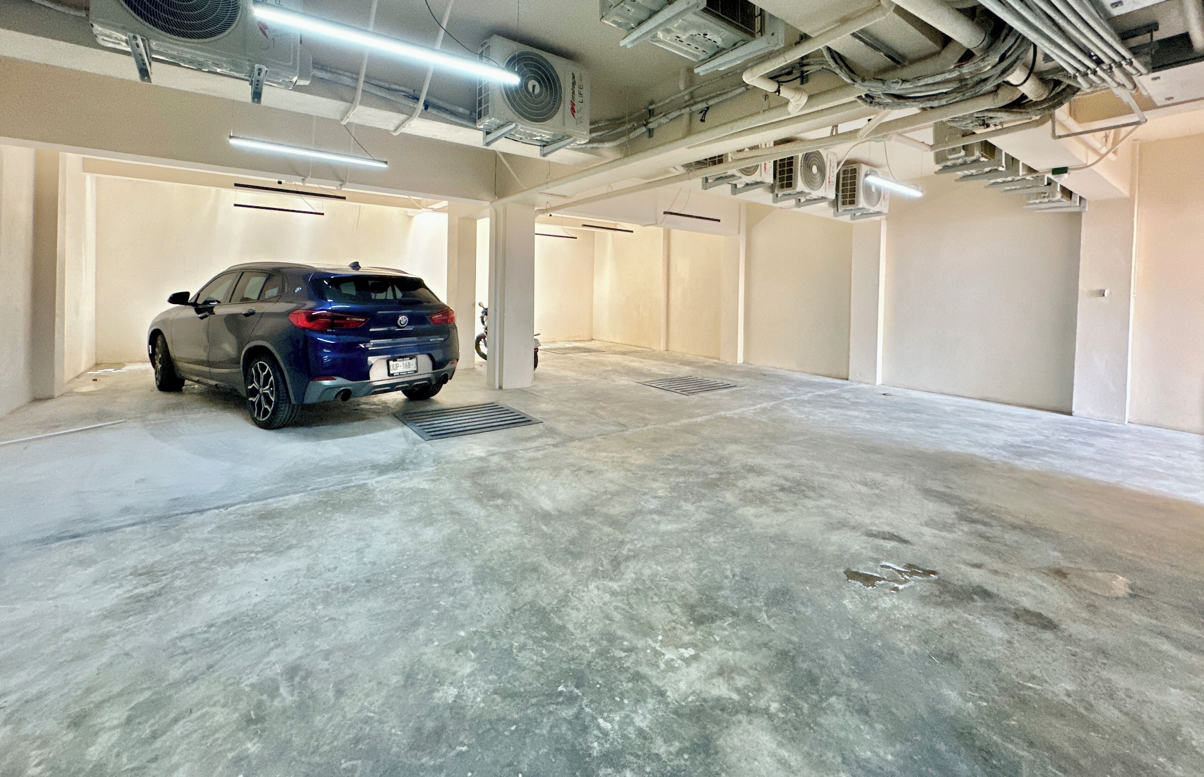 A parking garage with a blue car parked in a spot.