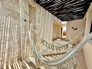 A hammock suspended between stone walls with a wooden ceiling and a view of a balcony. - CARIBIQUE (Playa del Carmen)